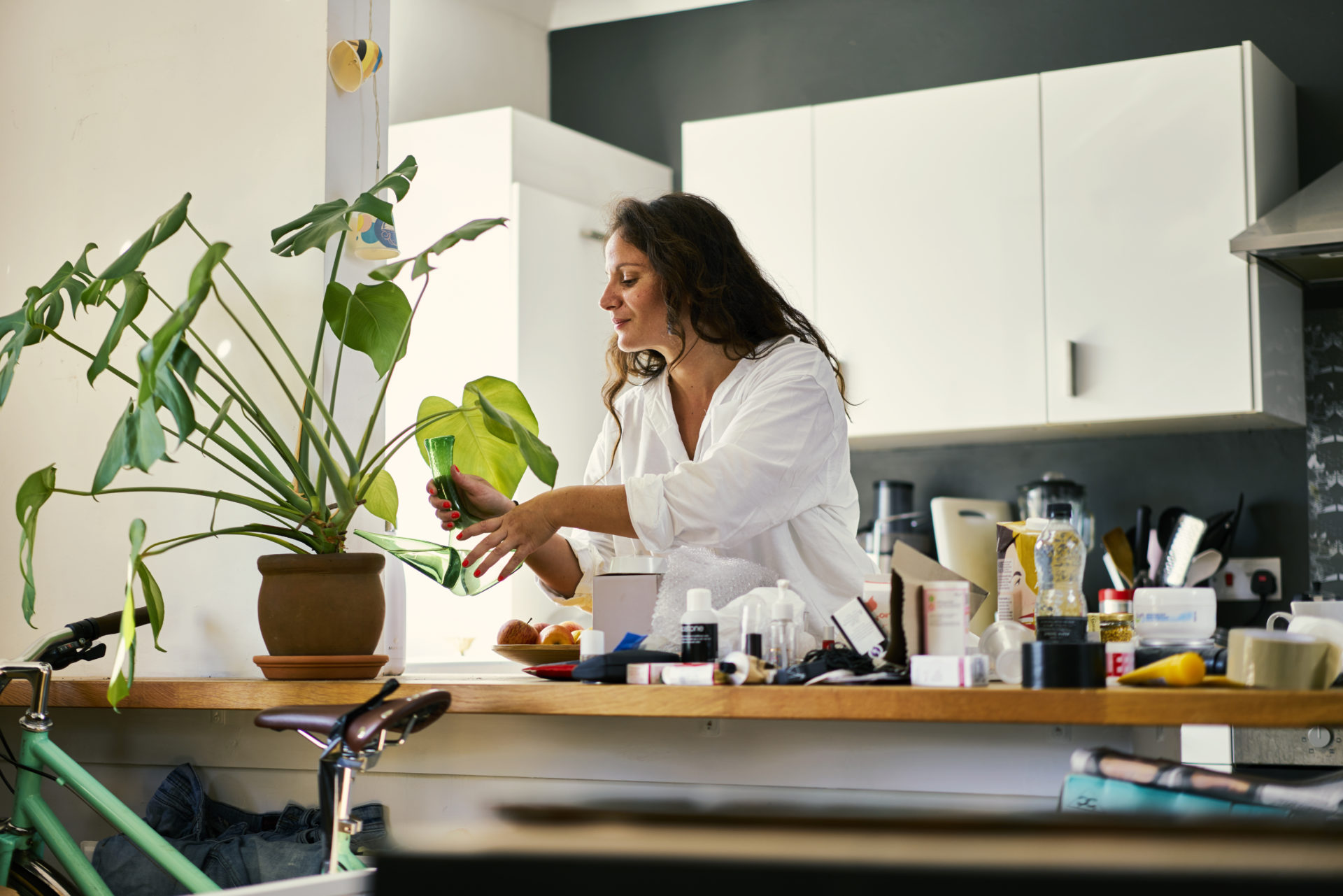 Mixed race woman watering her houseplant in the kitchen