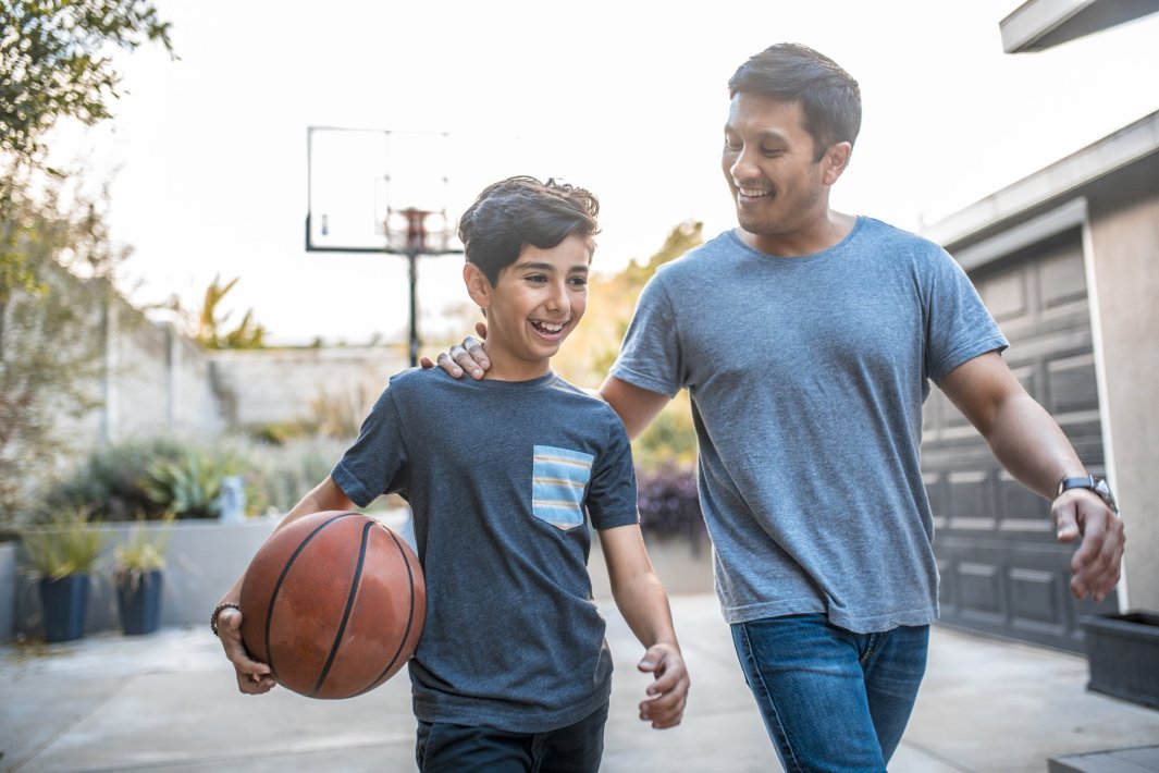 Father and son after basketball match on backyard. Son holding basketball.