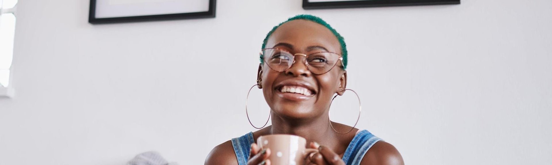 A black woman with short hair holding a coffee mug and smiling