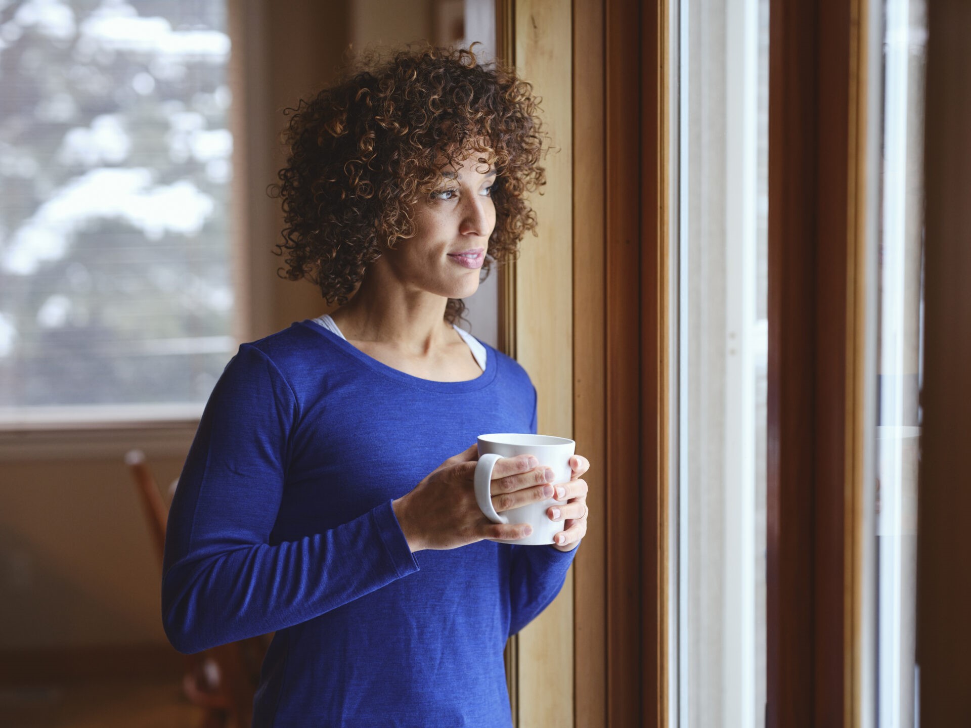 Woman in a Home Standing by a Window in Winter