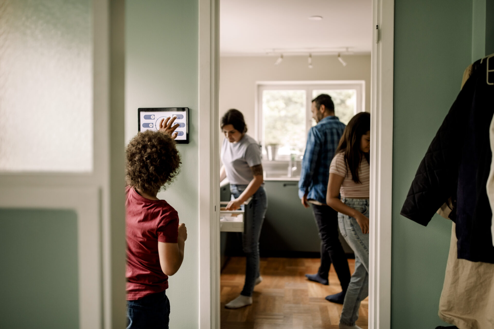 Boy using digital tablet while family in kitchen at home