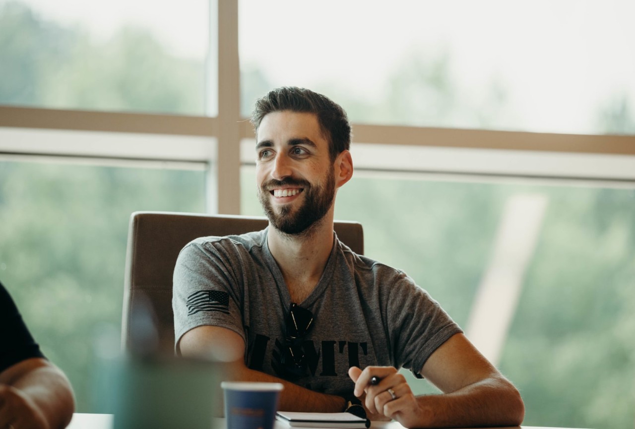 Man seated at a table looking off-camera and smiling