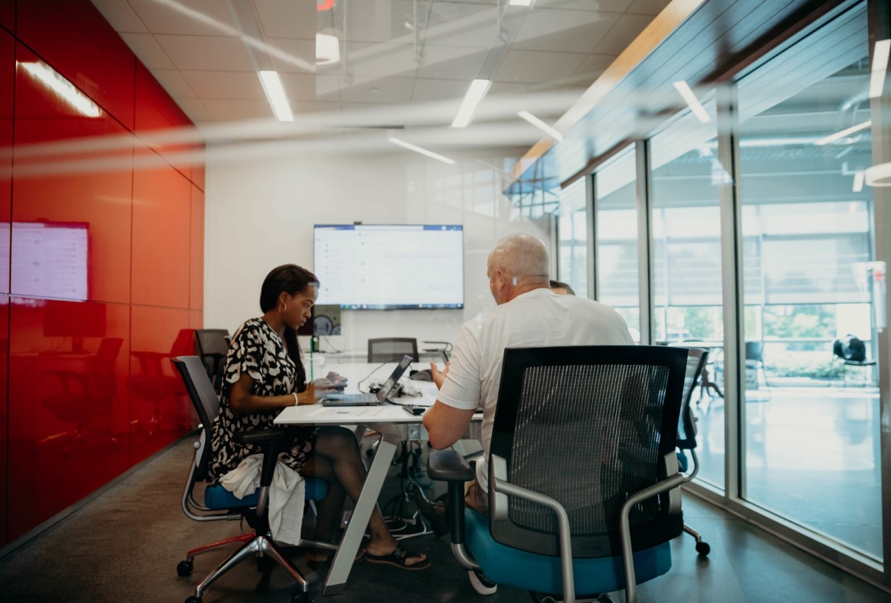 Meeting room with three people seated at a table working