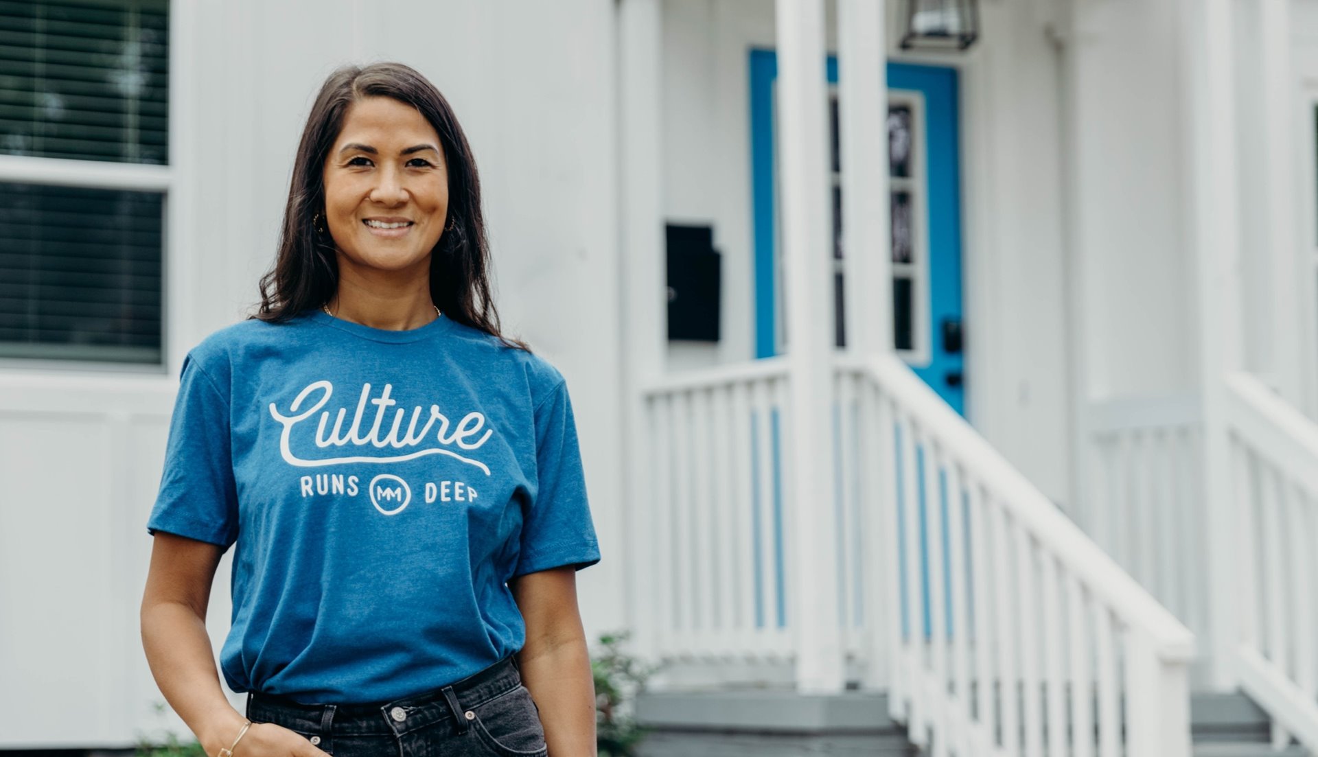 Woman with blue shirt standing in front of a house