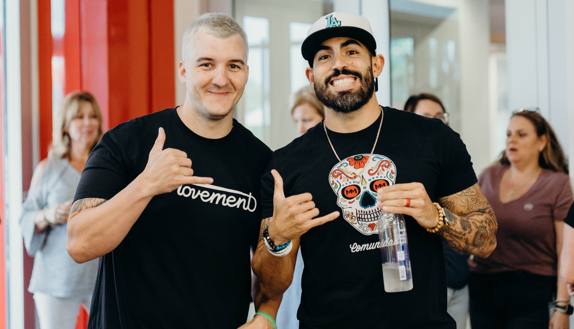 Two men smiling giving the "shaka" hand sign