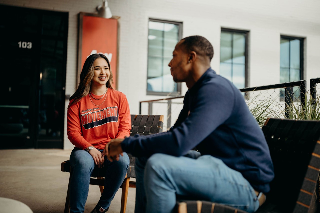 Two people seated and talking with each other